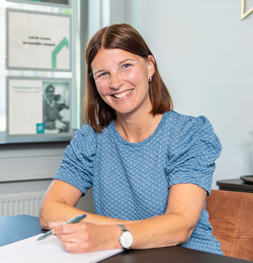Linda Heijmans met pen in de hand aan het bureau