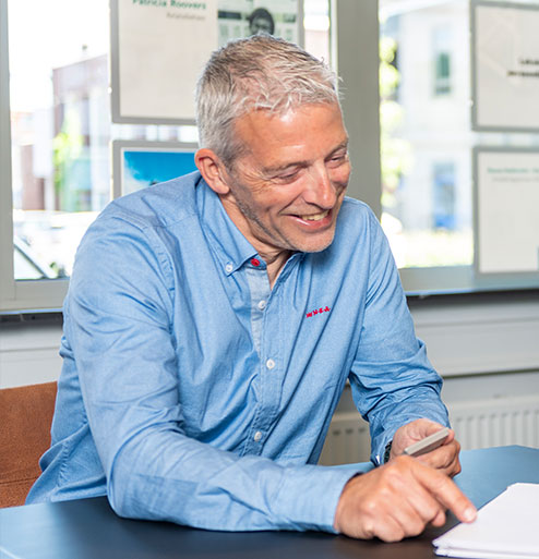 Roeb Slieker lachend naar papier op bureau bij Verbrugge Groep